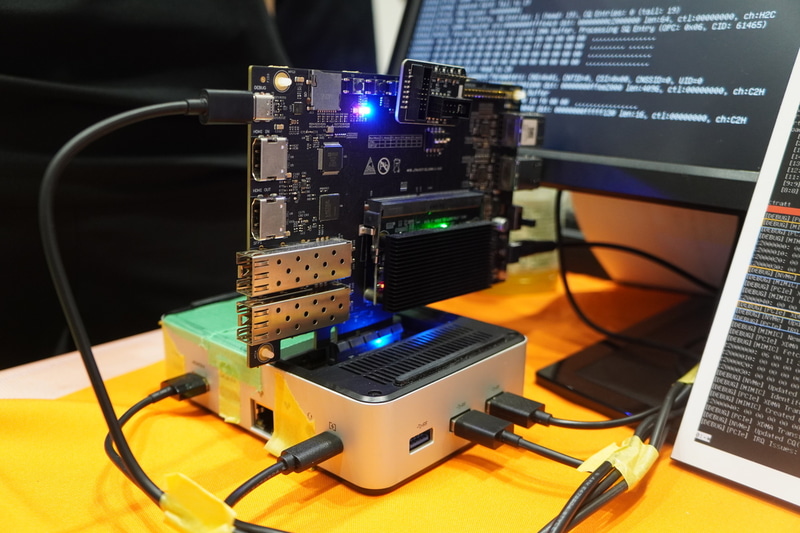 ミニPC（下）にPCIe接続した評価ボード（上）に、自作SSD（ボード右下の黒い長方形）が載っている