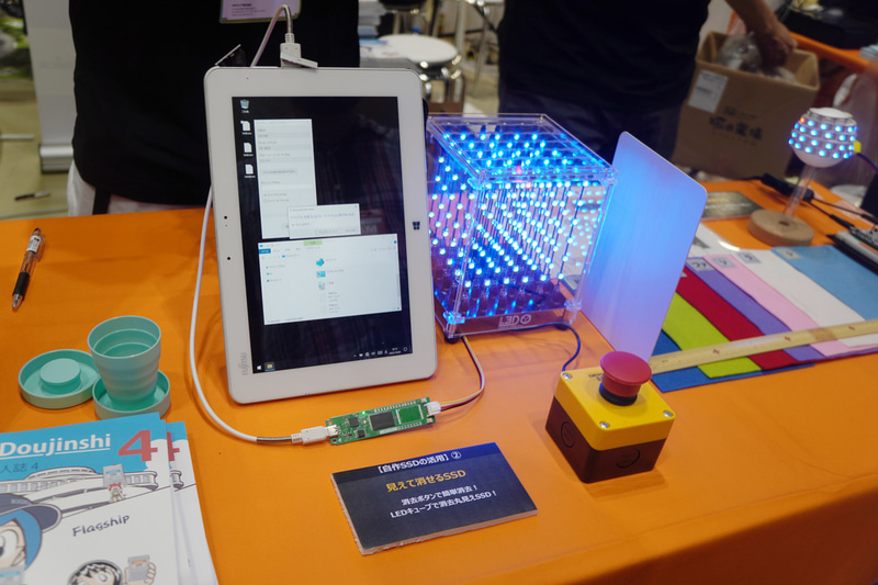 「見て消せるSSD」のデモ。モニターの下にあるのがJISC-SSD、モニターの右にあるのが可視化LED、右手前がデータ消去ボタン