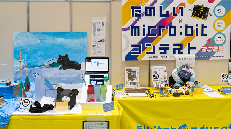 ブースでは決勝大会に勝ち残った6作品を展示。優秀賞には、折り紙遊びをmicro:bitで拡張した「ぴょんぴょんカエル飛ばしゲーム」（青木創太郎さん）と、機械学習を楽しく活用した「ウパザウルス～楽しい機械学習～」（ききららさん）が選出。その他、「なりきり！ 熊体験セット」「ブロッコリーのごみの分別ゲーム」「micro:bitでペンプロッタを作ってみた」の3作品が特別賞を受賞