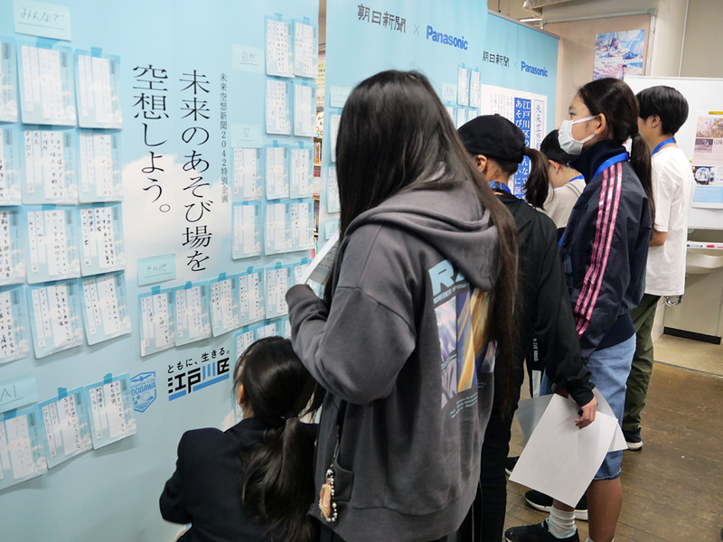 子供たちから寄せられた「未来の新聞の見出し」を読み込む参加者