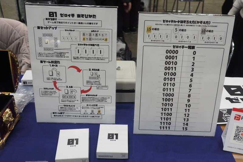 「ゼロイチ」は、山札をめくって出た数字を、手元にある4枚のゼロイチカードを使って素早く作った人が勝ちというゲームであり、2進法の勉強になる