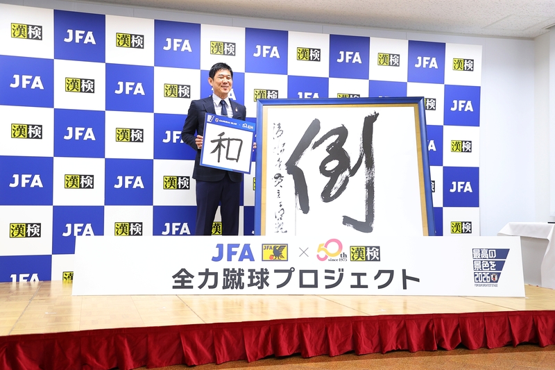 「決意の漢字」『和』を掲げるサッカー日本代表の森保 一監督と、1997年「今年の漢字」第1位『倒』大書レプリカ（2025年6月11日撮影）