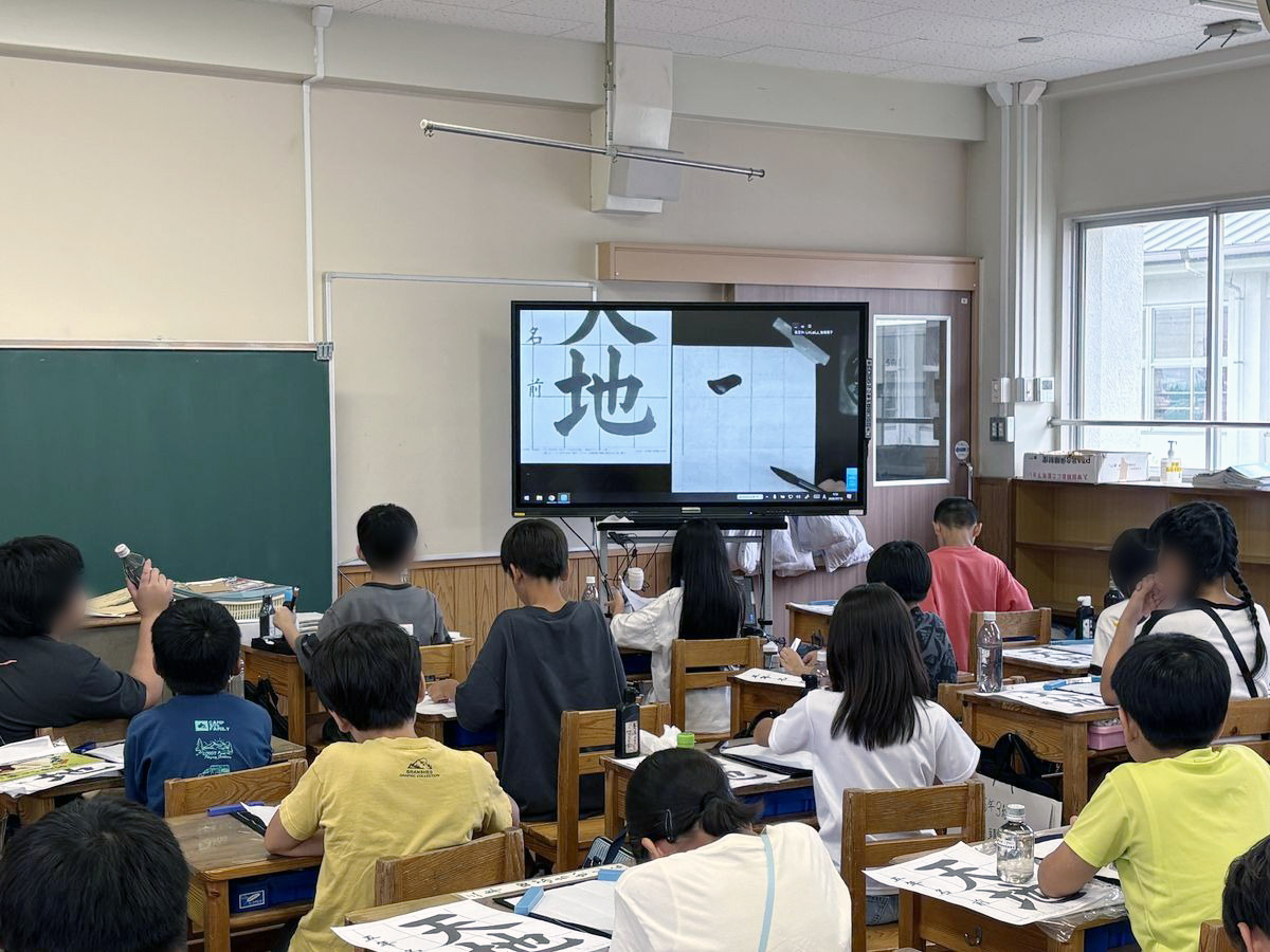 電子黒板に映る講師の筆運びを見ながら「天地」を書く小学5年生（出典：しゃしゅしょ株式会社、以下同じく）