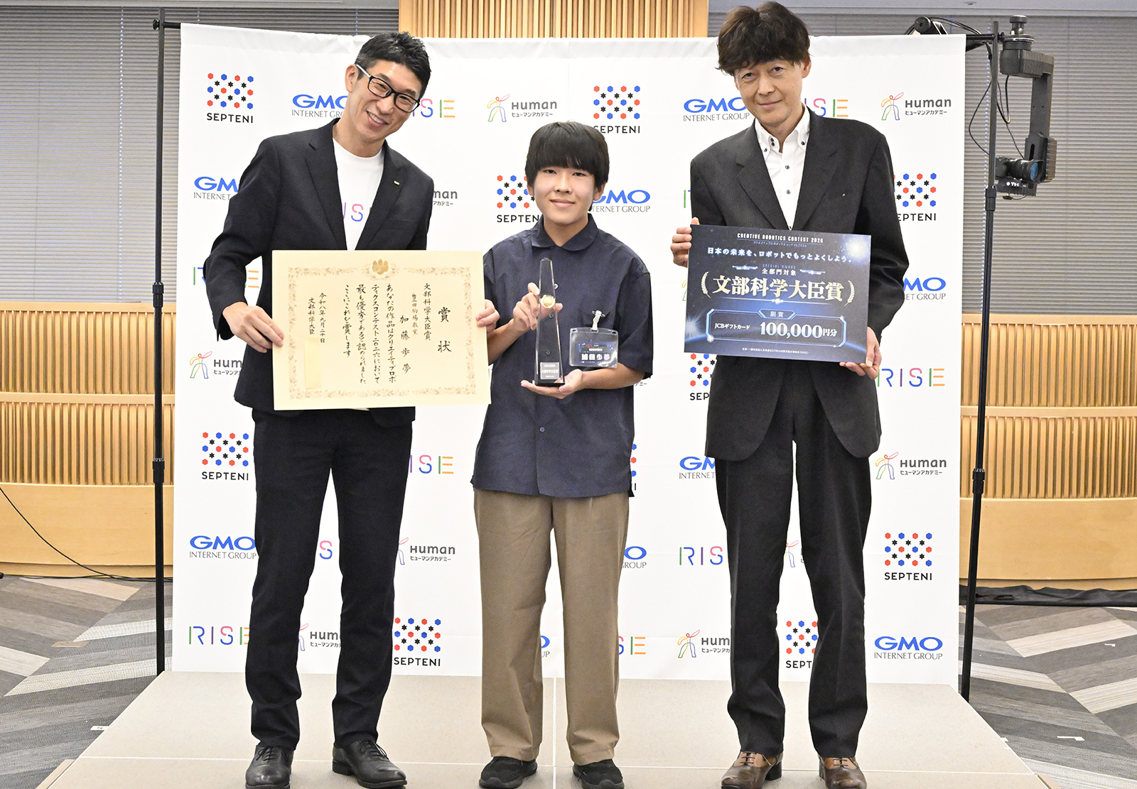文部科学大臣賞など3冠を受賞した加藤歩夢さん（中央）、ヒューマンアカデミー株式会社 児童教育事業部長の長谷川直之氏（左）、審査委員長を務めた千葉工業大学 未来ロボット技術研究センター（fuRo）所長の古田貴之氏（右）