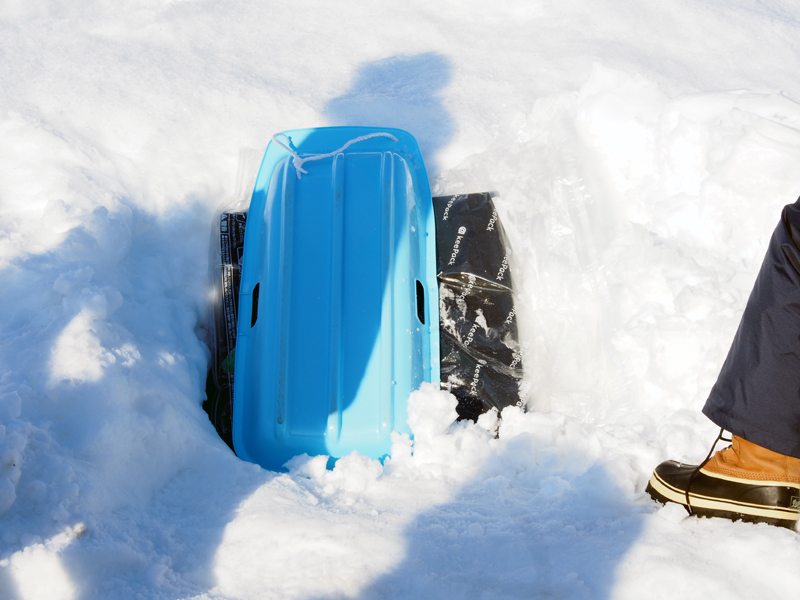 人形のポケットにスマートフォンを入れ、雪の中に埋めた