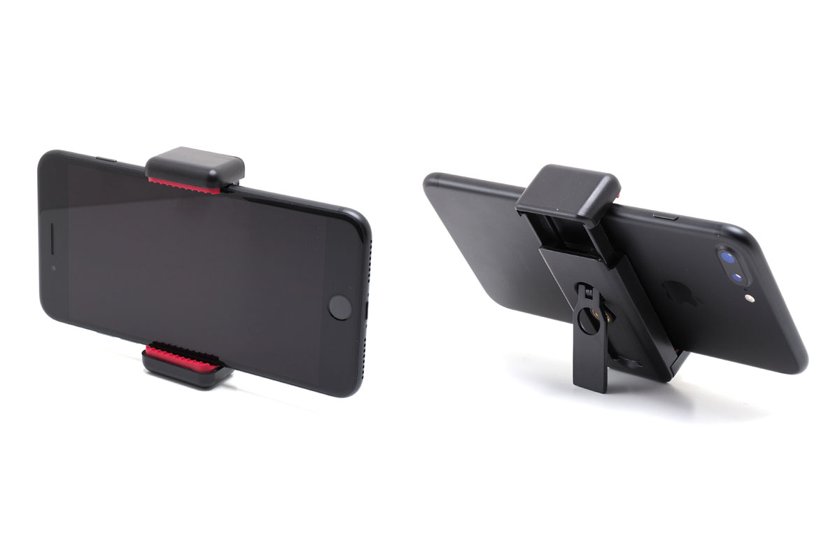 ちなみに、樹脂製の「スマートフォン用三脚アダプター」（<a href="https://www.manfrotto.jp/universal-smartphone-clamp-with-thread-connections" class="n" target="_blank">公式ページ</a>）という製品もあります。こちらはバネ式で、底面と背面に三脚ネジ穴があります。簡易的なスタンド機能も。メーカー価格は税別1500円。