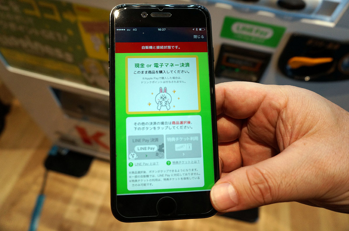 自販機で買いたい商品を選びボタンを押しつつ、画面で支払い方法を選ぶ