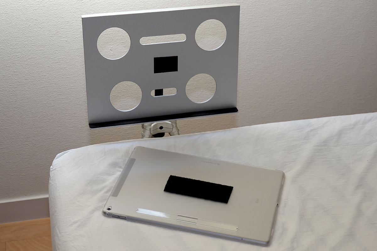 置くだけでは不安という場合、タブレットをケースに入れ、ケースと「カメラ三脚用ノートPCデスク CLHCMAL2」に面ファスナーテープ（貼り付け用粘着テープ付き）を貼り、簡易的に固定する方法もあります。ただこの方法だと、ケースの材質やテープを貼る大きさなどにより、面ファスナーテープが剥がれてしまうこともありますので注意が必要です。耐震用の粘着パッドを貼る方法も良さそうです。