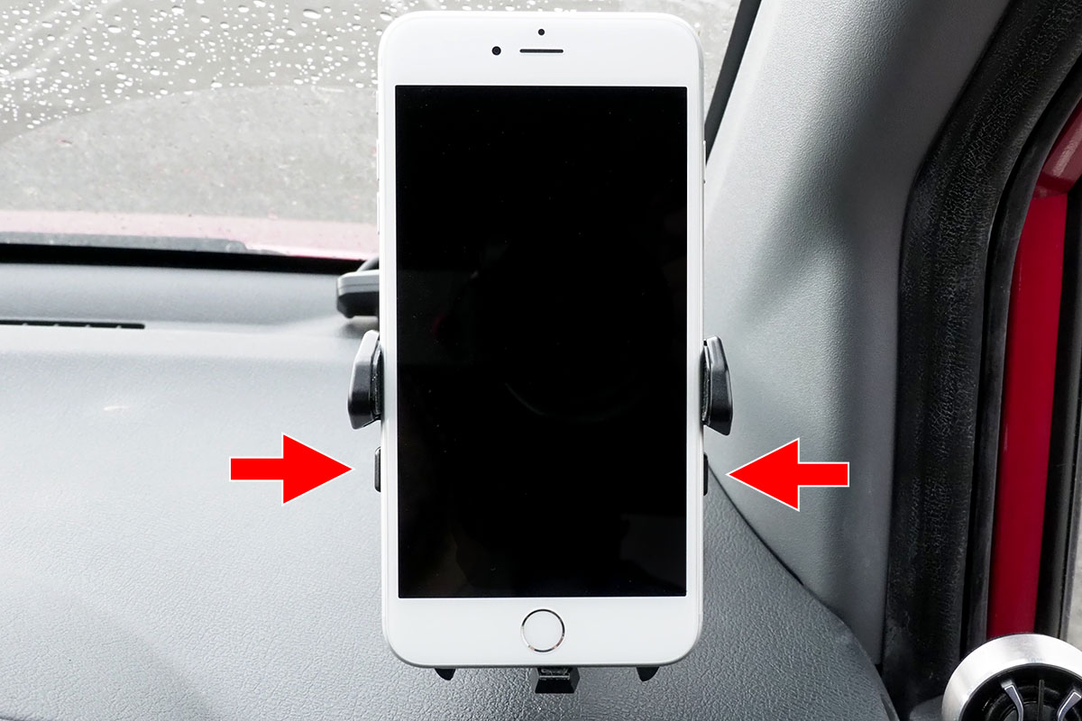 片手でホルダーから外すこともできます。赤矢印の部分を指で押すとホルダーが開きますので、そのまま端末を引き抜けばOK。その状態でホルダーが開いたまま固定されますので、再度端末をホルダーに置けば自動的に保持。脱着が片手で行える自動ホルダーというわけです。