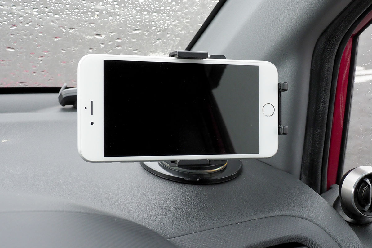 車内に設置した様子。ホルダー中央の丸いボタンが押されるようスマートフォンを置くと、自動的にホルダーが閉じて端末が固定されます。端末の向きや角度も十分な自由度をもって調節できます。