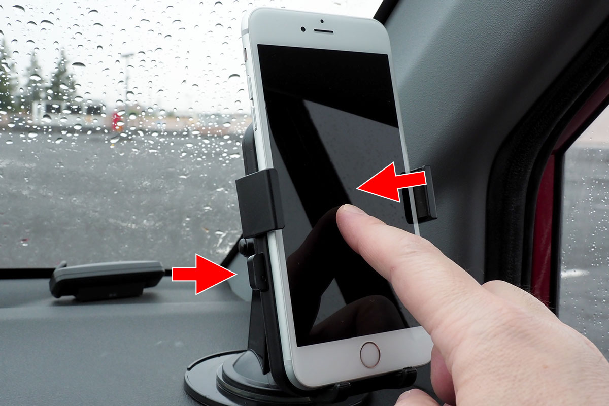 左右のボタンが押し込まれた状態で、端末を置きます。軽く置いて、画面中央をポンと押してホルダーの丸いボタンを押してもいいでしょう。ホルダーが閉じて端末が保持されると、ホルダー左右のボタンが少し飛び出します。