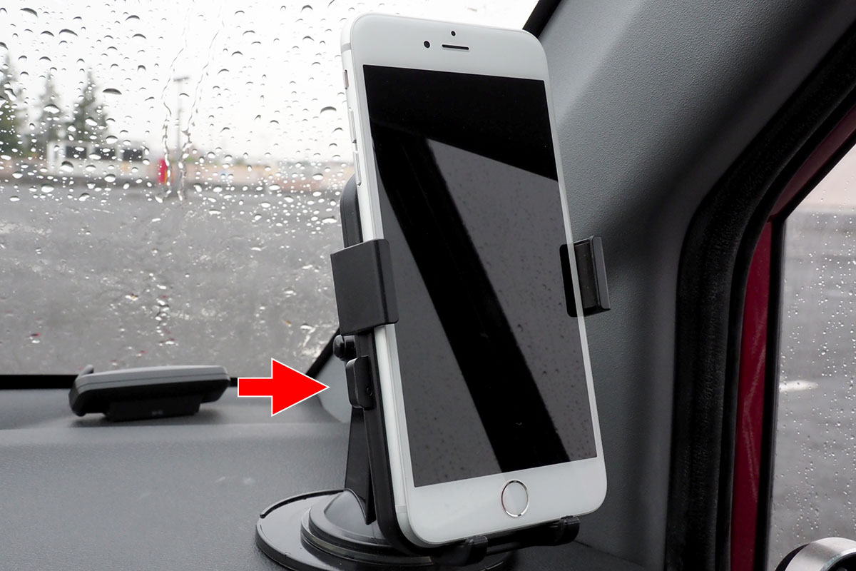 左右のボタンが押し込まれた状態で、端末を置きます。軽く置いて、画面中央をポンと押してホルダーの丸いボタンを押してもいいでしょう。ホルダーが閉じて端末が保持されると、ホルダー左右のボタンが少し飛び出します。