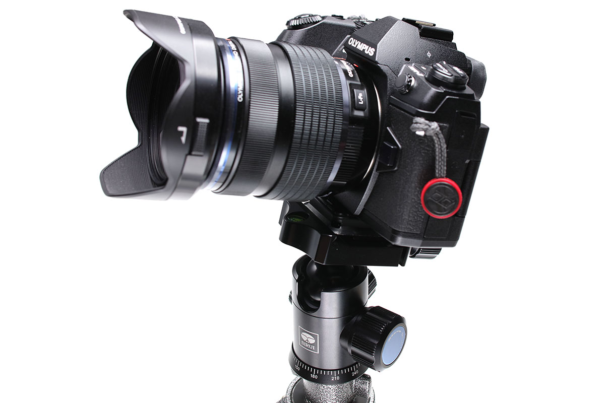 オリンパスの「OM-D E-M1 Mark II」とズームレンズ（12-40mm）や望遠レンズ（300mm）を組み合わせて、雲台にセット。安心感のある固定力です。フリクションの調整により、ノブを緩めたときの「突然かつ急激なカメラのおじぎ」を回避できます。300mmのレンズは、三脚座がじつはアルカスイス互換なので、そのままアルカスイス互換雲台にセットできます♪