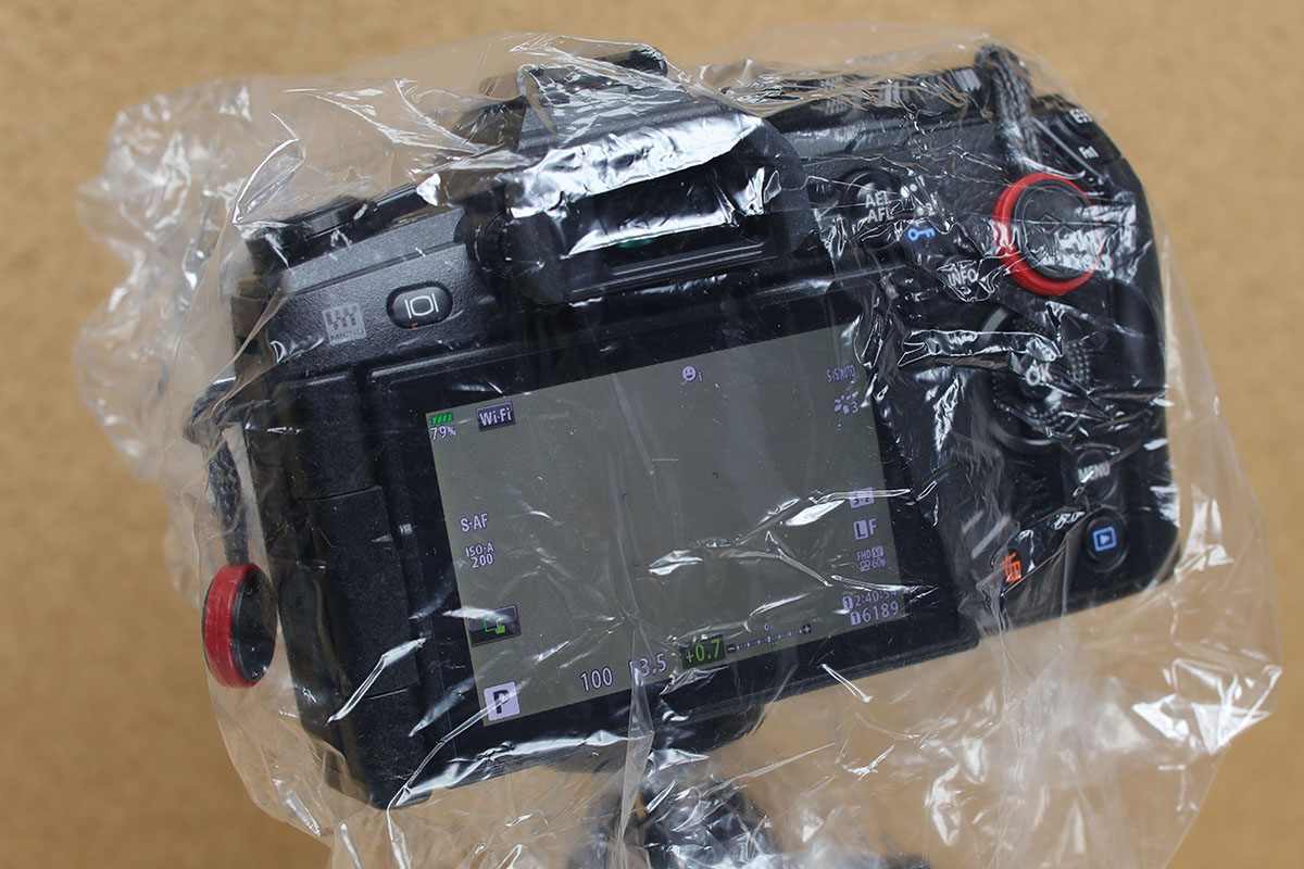 レンズフードの上にシャワーキャップを引っ掛けるようにすれば、そのまま撮影することもできます（焦点距離によってはケラレることもあるのでご注意）。各部の操作も可能ですので、つまり雨中での撮影もOK。ただしファインダー類はちょっと見づらくなります。接眼部に穴を開けちゃうのもアリですね。