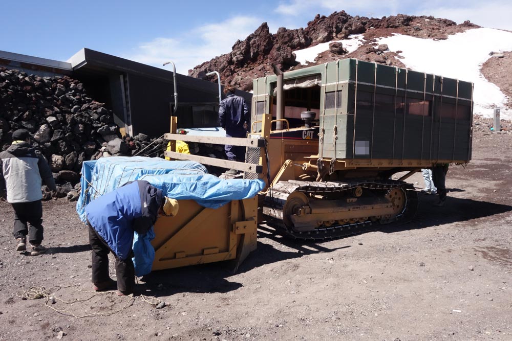 荷下ろし作業。ドーザーショベル部が荷台になっていて、車体側にキャビンが増設されている