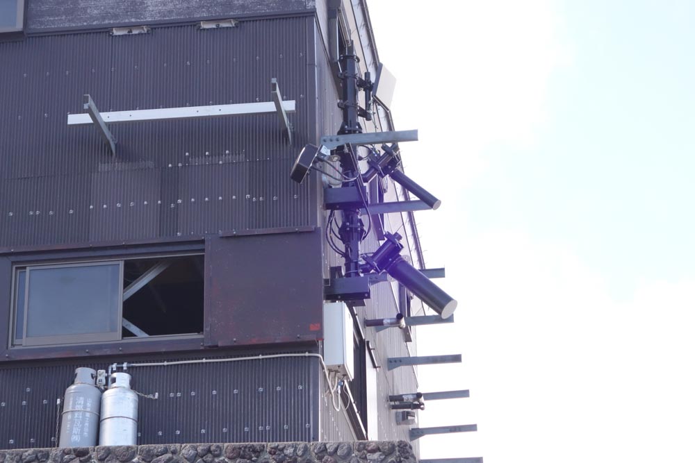 本八合目の山小屋壁面に設置された基地局。茶色い筒状アンテナ2本と箱状アンテナ1個がLTEで、一番上の白い板状アンテナが無線エントランス