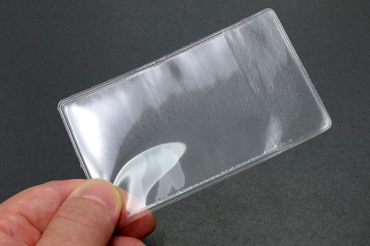 「貼るタイプのカードポケット」の一例。多くは透明の極薄樹脂製ポケットで裏面がシールになっていて、どこにでも貼って使えます。貼れば名刺やカードが入るポケットを追加できるという小物。写真ではわかりやすいように手帳の表に貼っていますが、手帳やノートなら内側に貼ることのほうが多いかしれません。でも、貼れる平面にならどこに貼ってもOK。