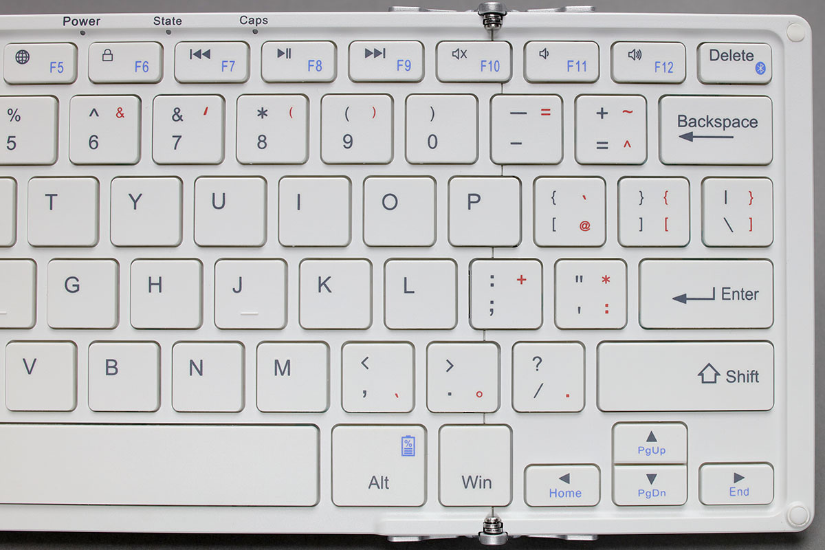 キー配列は英語配列で、主要なキーは標準サイズのテンキーレスキーボードと同じサイズ/キーピッチ（19mm）です。赤の刻印はWindowsマシンと組み合わせたときの入力を示しますので、Windowsマシンと組み合わせたときは変則的な配列が目立つかもしれません。