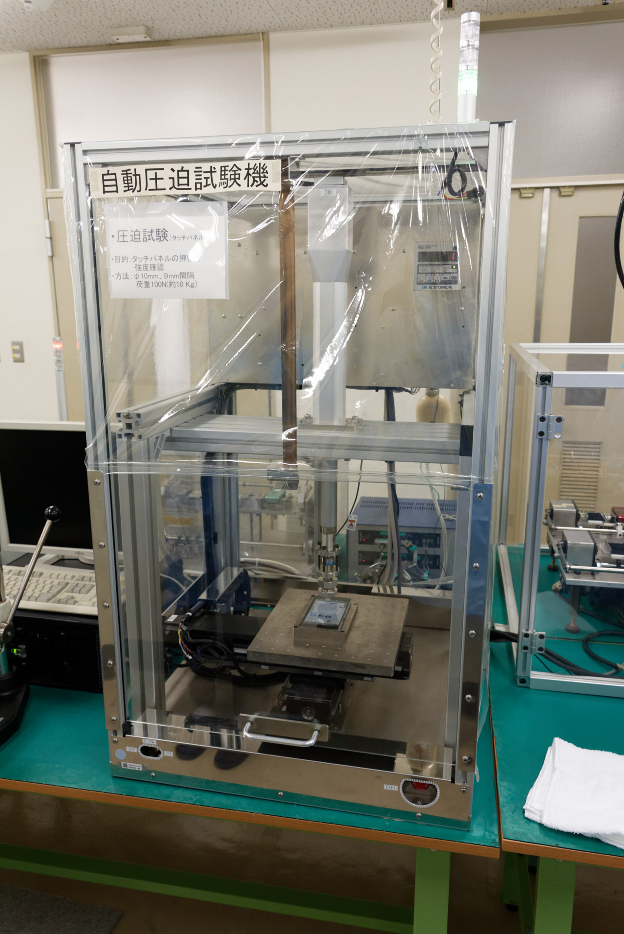 タッチパネルに対する自動圧迫試験。タッチパネル全体を100箇所前後、先端直径10mmの機材で10kgの荷重を加え、耐えることを確認する