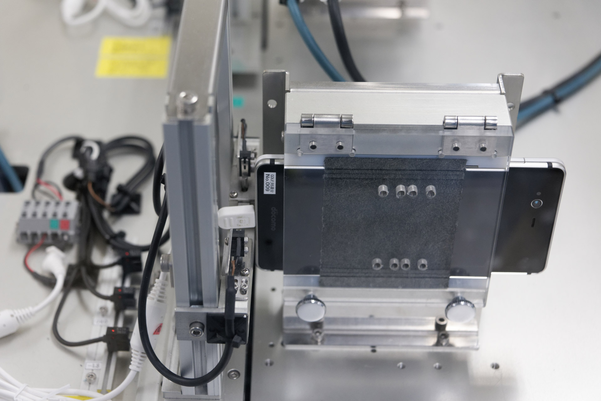 コネクタ耐久試験。USBケーブルを接続した状態で、コネクタの根元に上下および左右方向から2kgの力を5000回ずつ加え、問題ないことを確認する