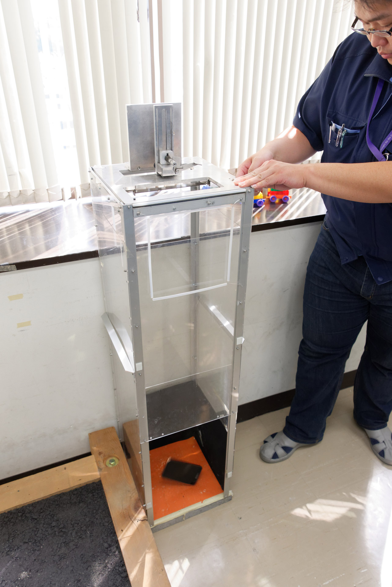 こちらは従来型の試験機。スマートフォンを載せた天板を開いて自由落下させるものだが、落下中に方向が変わってしまうため、狙った角度で落下させるのには不向きだった
