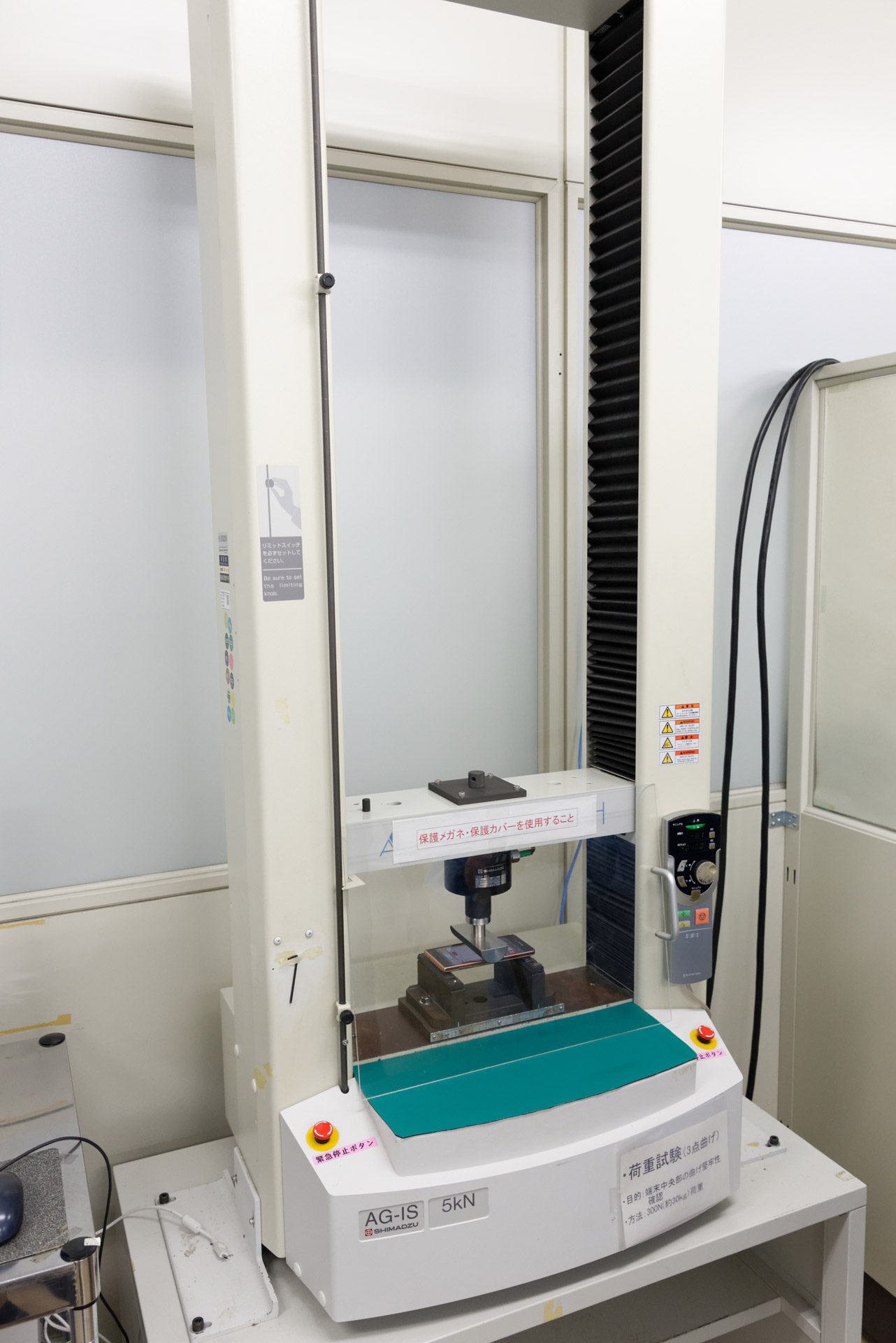 荷重試験。端末中央部に30kgの荷重を加え、問題ないことを確認する。ズボンのお尻ポケットにスマートフォンを入れて、そのままイスに座ったときのことを想定したもの