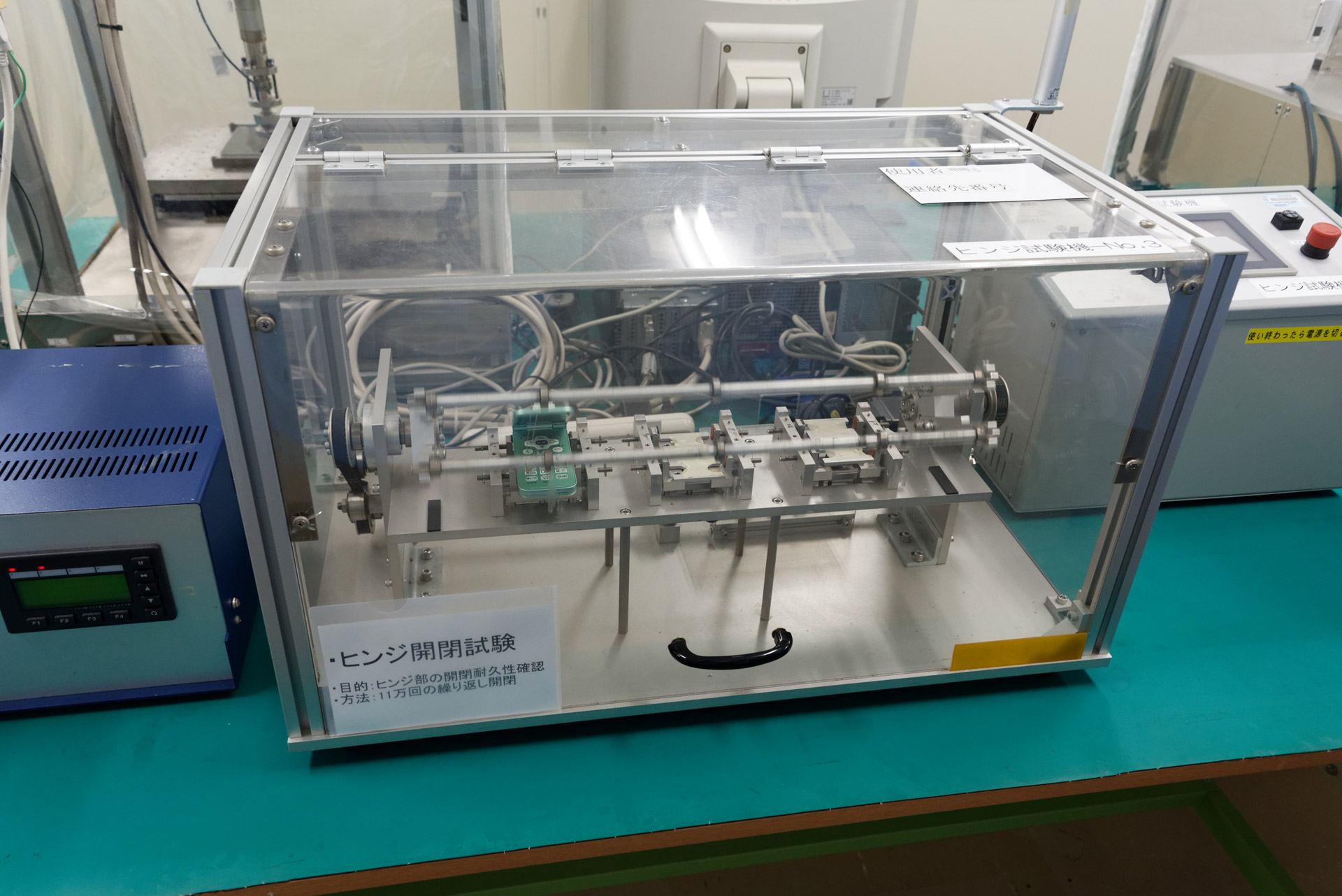 折りたたみ型携帯電話の開閉を11万回繰り返す、ヒンジの耐久試験を行う機材もある