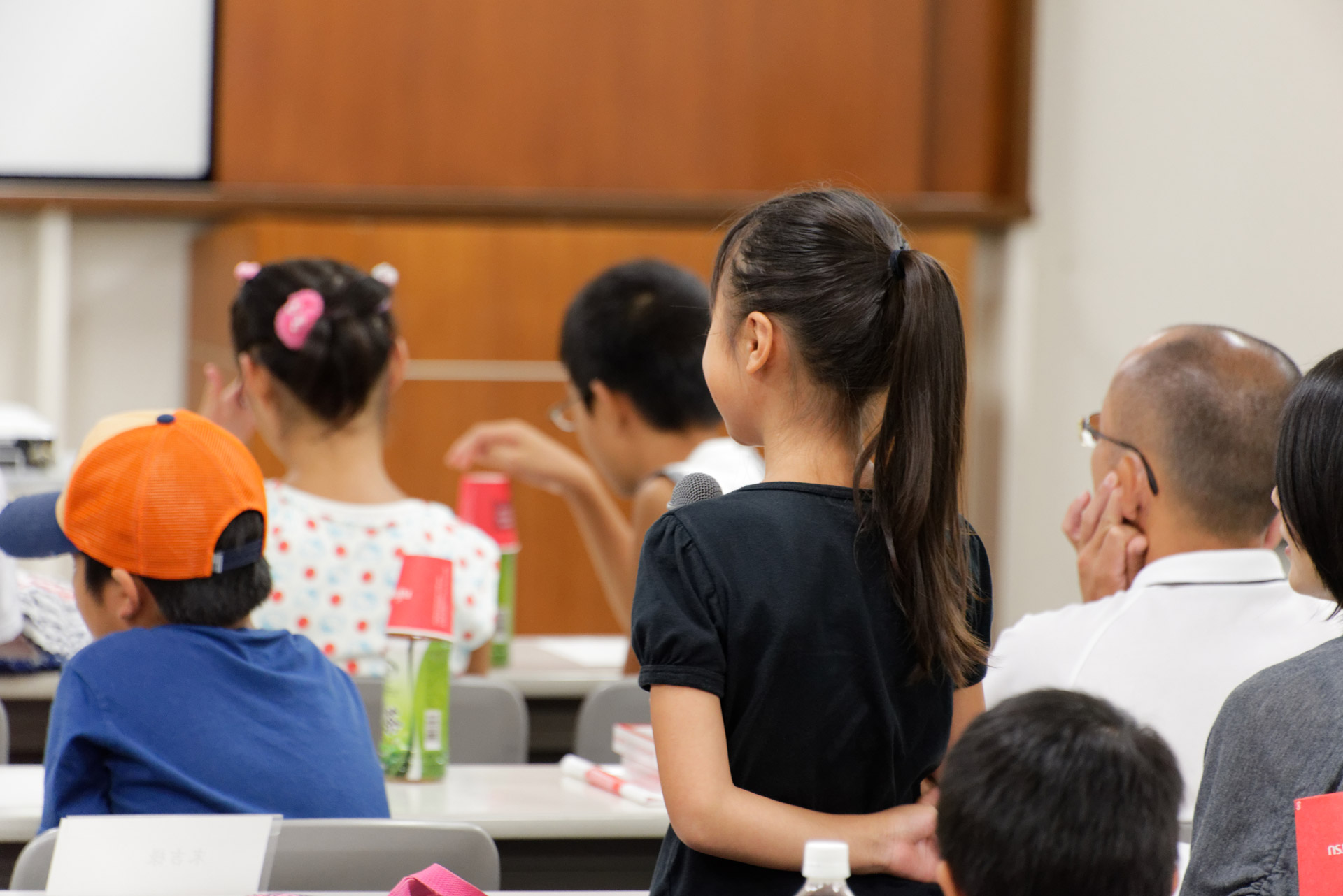 工場の社員に積極的に質問する子供や、説明を聞いて熱心にメモを取る子供の姿も