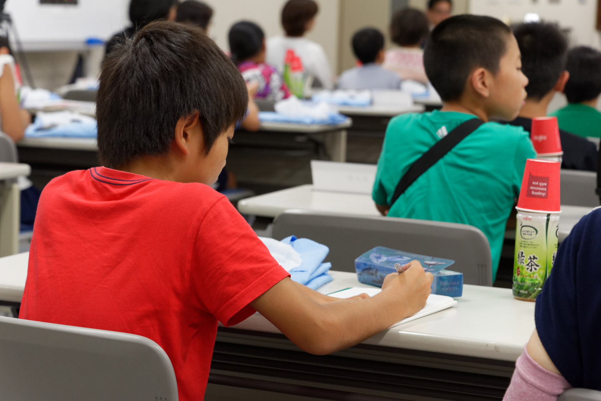 工場の社員に積極的に質問する子供や、説明を聞いて熱心にメモを取る子供の姿も