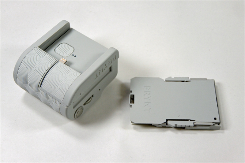 本体（左）に専用紙をセットしたカートリッジ（右）を差し込み、さらにLightningコネクター部分にiPhoneをセットして使用する。シャッターボタンも付いていて、このままカメラのグリップのようにして撮影することも可能だ