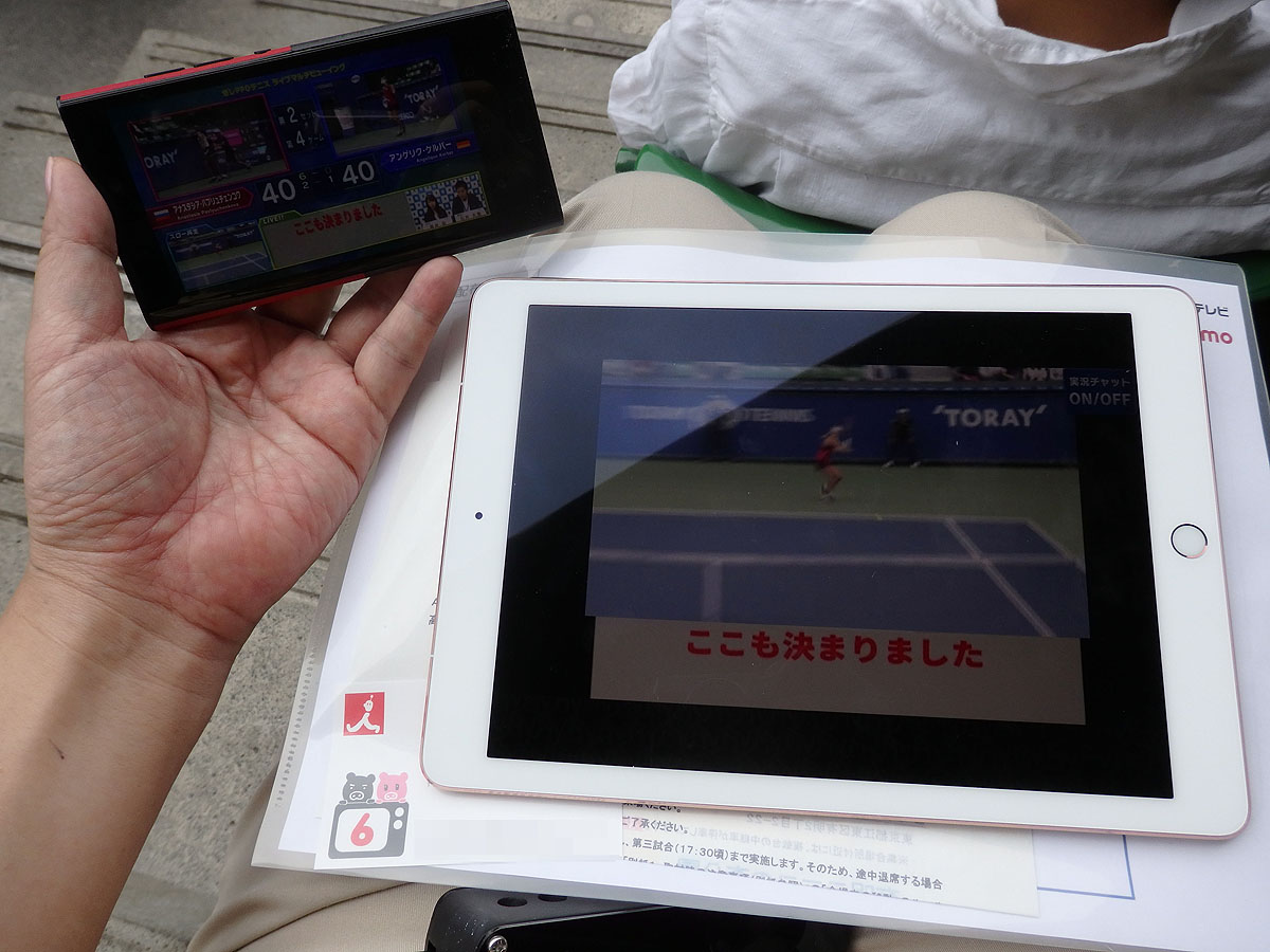 試合後半では片手にマルチ画面のスマートフォンを、膝にリプレイ表示専用のiPadを抱えて観戦するスタイル。主にコートをみて、気になったら、左手、膝、とチラ見