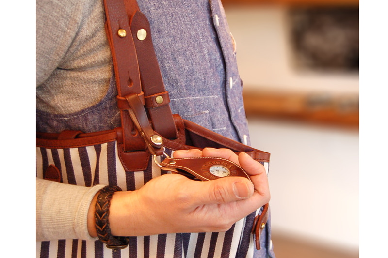 池之端銀革店の「Cramp【イタリアンレザー】懐中時計 （レザー本体）【Tc-110】」。時計を覆うタイプのホルダーで、付属のストラップとチェーンは脱着可能です。ストラップのループはスナップボタン式で、これを利用して吊したりできます。チェーンの端にもスナップボタン式のループがあり、これをバッグやベルトループなどに通して止めれば時計の落下防止になります。カラーは7色から選べます。※写真はメーカーサイトより抜粋/ホルダーに時計は付属しません。