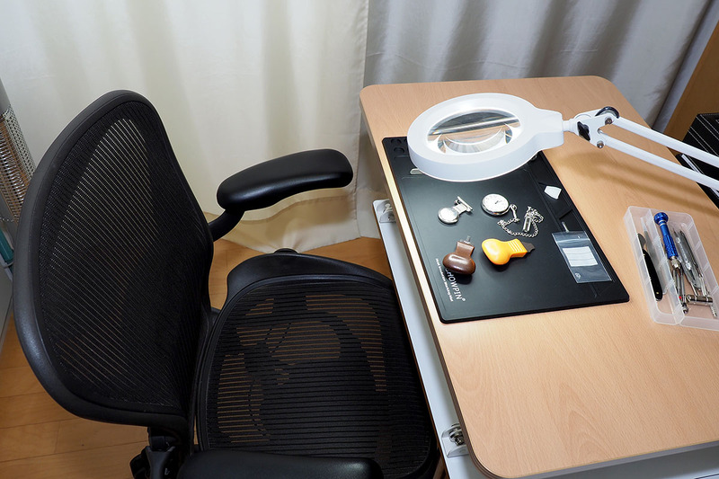 仕事机の片隅で「スタンディングデスク 100-MR110」を使っている様子。机面サイズは幅700×奥行き500mmでわりと小型。作業台としてちょうどいいです。ハンダ付けのときは低めに、時計いじりのときは高めに、といった感じで自由に高さを調節できます。