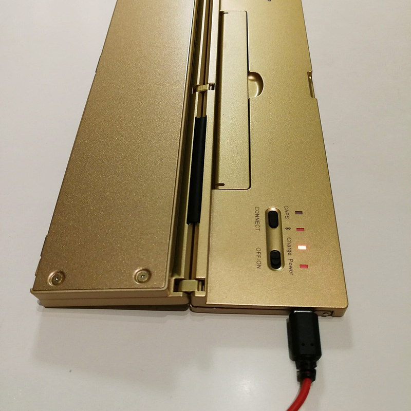 充電中のBATTOPキーボード。指掛け穴から引き起こすとスタンドの受け板になる