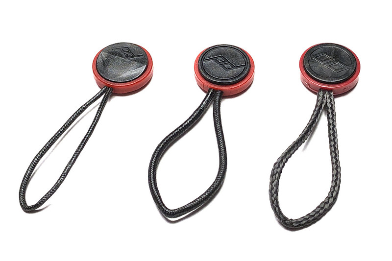 写真左は、左側が新型アンカーで、右側が旧型です。新型アンカーは、ヒモが接続されている箇所の近くが斜めになっています。この形状によりストラップとの脱着が非常にスムーズになりました。写真右は、歴代アンカーで、左側から最新型、やや古いタイプ、さらに古いタイプです。最新型のヒモは細めなので、デジカメのストラップホールにより通しやすくなりました。ちなみにこれらアンカーの耐荷重はどれも90kg（1個につき）。