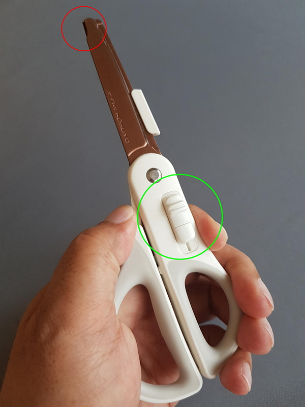 緑丸の中のハコアケモードスイッチを前に押し出し、ハサミのグリップをしっかりと握ると、赤丸の先端位置にハサミのもう一方の刃先が露出してカッターになる仕組み