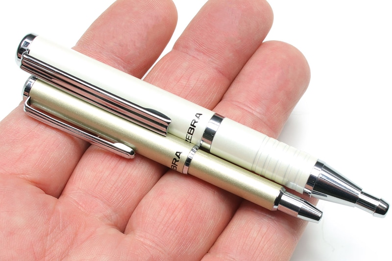 ゼブラ「SL-F1」シリーズ。シャンパンゴールドっぽい銀が細め短めの「SL-F1 mini」で、白が太め長めの「SL-F1 ST」です。どちらも伸ばすとボールペンが露出して筆記できる状態になり、縮めるとボールペンが格納されて携帯できる状態になります。
