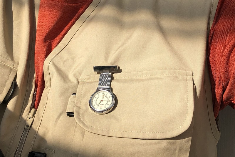 こんなふうに衣服（ホントは白衣）にピン留めして使います。手で文字盤を起こせば時間がわかるのはもちろん、文字盤を覗き込むようにすれば手を使わずに時間を知ることができます。右写真は、ナースウォッチ装着者の視点で文字盤を覗き込んだ様子。