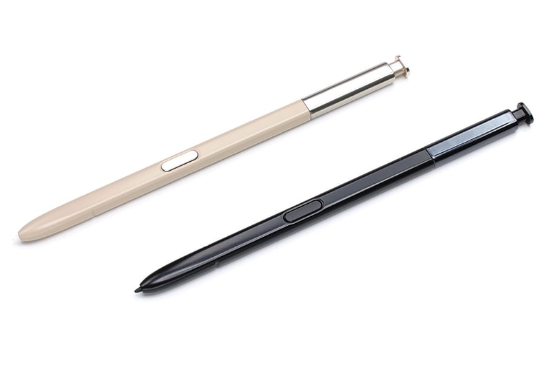 写真左は、ベージュがau版のSペンで、ブラックがドコモ版。両色とも両キャリアにあります。外観は全く同じで、au版Sペンをドコモ版Galaxy Note8にセットできました。Sペンを引き抜くと立ち上がる「画面オフメモ」機能やエアコマンド機能が使えるあたりも同様です。写真右は、Galaxy Notesアプリのグリッドに沿って線を描いた様子。左がau版Sペンの筆跡で、右がドコモ版Sペンの筆跡です。どちらもペン先と筆跡がズレる感じはなく、自然に描けました。