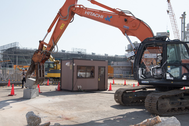 遠隔操作される無人のバックホー、日立建機「ZX210」。瓦礫の撤去などを想定したグラップル装備で、50cm角のコンクリートブロックの積み上げを披露