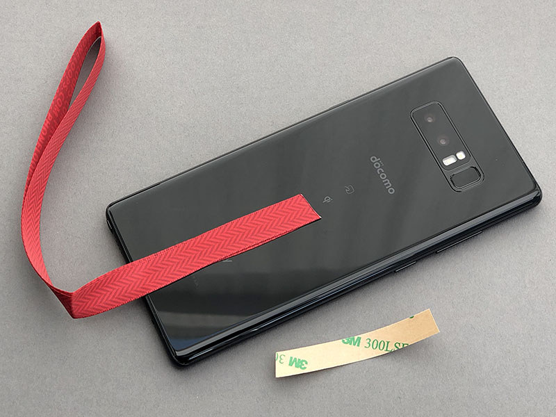 使いやすい位置を見つけ、そこにペタリと貼ります。さらに保護カバーを装着。リボン接着部が端末背面と保護カバーで圧着されつつ挟まれる感じですね。両面テープには十分な粘着力がありますが、わりと剥がしやすいという感じ。貼ったり剥がしたりを何度か繰り返せます。