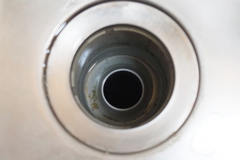 仕事場の排水口から銅製ゴミ受けを外した状態。若干の黒っぽい汚れが見えますが、全然掃除していないわりにはかなりキレイです。銅製ゴミ受けを置く前は、2～3週に一度はまっ黒にヌメった排水口を掃除していましたが、銅製ゴミ受けを置いてからほとんど掃除レスに。