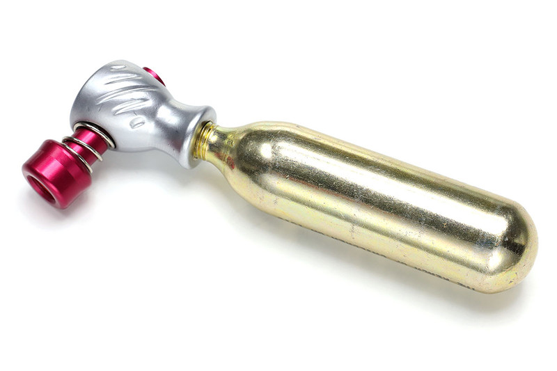 最もシンプルな類のCO2インフレーター。この製品の場合、ノズル部の下にCO2ボンベをネジ込み、その状態で赤いノズルをタイヤのバルブに強く押し当てると、ほぼ一瞬でタイヤに空気が入ります。コンパクトで軽いため、自転車での常時携行にもよく向きます。なお、CO2ボンベは使い捨てで、1本300円前後で売られています。