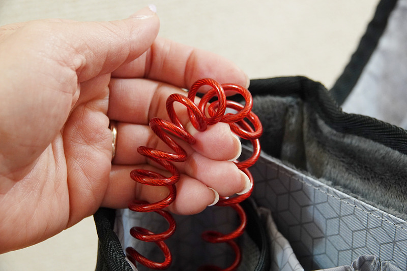 バックパックのポケット部に内蔵されているコイル状のスチールケーブル。結構硬い（左）。その先端に取り付けられた3桁の暗証番号式ロック。暗証番号は好みのものに変更可（右）