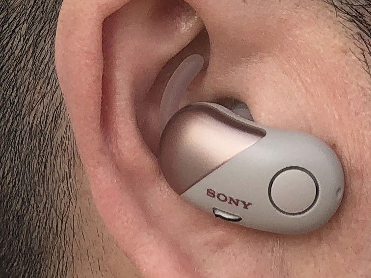 装着例。耳の穴に入るイヤーピースと、耳の外側の凹みに沿うように当たるアークサポーターにより、しっかりと装着できます。しっかり装着できつつも、その装着感が自然なのがナイス。あと、耳に対する脱着も容易で、「耳に入れて少し回すだけ」「耳から抜くだけ」という感覚。スムーズに使えます。左右のイヤホンにはボタンが1つずつあり、位置は下側。探しやすく押しやすいボタンです。