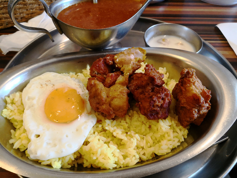 昼間の自然光が主体の窓際で、やや暗い店内。色合いは自然だがライスがやや味気ない