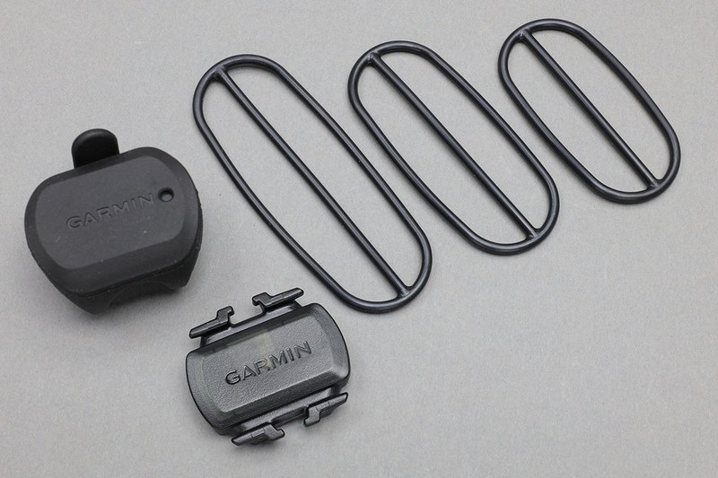 自転車に取り付けるセンサーと固定用Ｏリング。Ｏリング部分はモビロンバンドで置き換えられます。モビロンバンドを2～3本を重ねて使えば十二分な固定力と強度が得られます。モビロンバンドはＯリングより薄く細いことが多いので、重ねて使っても問題が出にくいです。また、モビロンバンドはＯリングよりずっと安価なので、整備毎に交換する「使い捨て利用」も現実的です（モビロンバンドには耐油性や耐候性があるそうですが、劣化はしますのである程度の期間使ったら交換するのが無難でしょう）。透明のモビロンバンドを使えば、自転車のデザインを損ないにくく、より自然にセンサー類を装着できるというメリットもありますネ。