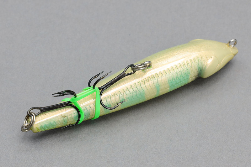 タックルボックスのなかにルアーをそのまま入れておくと、フックが絡まってルアーどうしが合体状態になりがち。ヘタをすると全ルアーが合体！　という「ルアー釣りあるある」も。それぞれのルアーのフックを写真のような感じで固定してしまうと、ルアー絡まり問題を大幅に抑えることができます。普通の輪ゴムでもできますが、釣りのシチュエーションは水気が多く直射日光もあるためか、輪ゴムだとすぐボロボロに。