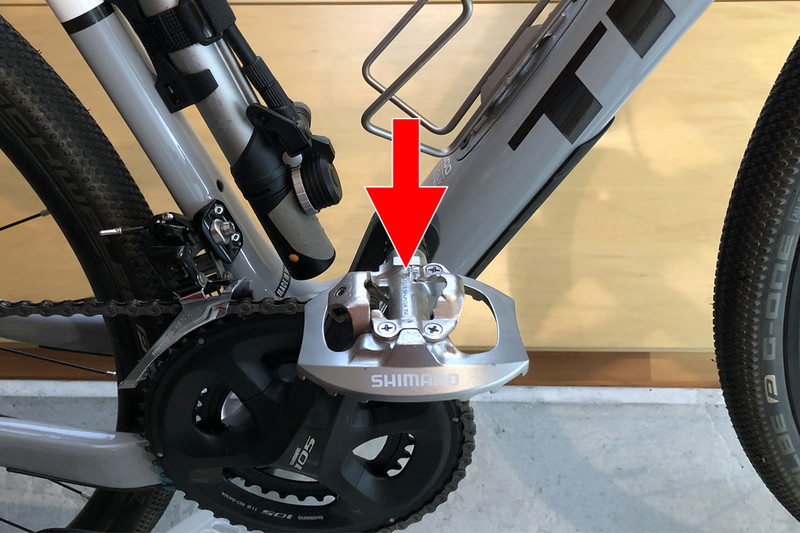 左はビンディング対応シューズの裏側で、矢印の金具がクリートです。この金具がペダル側の金具にはまり、シューズとペダルが一体化するというしくみ。ペダルにシューズを乗せて踏み込めばパチンと固定されます。固定された状態でシューズを外側にひねればカチャリと外れます。
