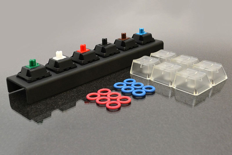 WASDで売られているサンプラーキット各種。左が「WASD 6-Key Cherry MX Switch Teste」(<a href="http://www.wasdkeyboards.com/index.php/products/sampler-kit/wasd-6-key-cherry-mx-switch-tester.html" class="strong bn" target="_blank">公式ページ</a>)で、チェリーMXキーの緑/白(クリア)/赤/黒/茶/青にクリアのキートップがセットされた「押し心地を試すためのサンプル」です。右は「WASD Keycap, O-Ring Sampler Kit」(<a href="http://www.wasdkeyboards.com/index.php/products/sampler-kit/wasd-sampler-kit-o-ring-keycaps.html" class="strong bn" target="_blank">公式ページ</a>)で、キーの樹脂色サンプル。どちらのサンプラーにも、カスタマイズ時に「Sound Dampeners」と表示されたパーツ(Oリング)が付属しています。キーボードを買う前にこれらがあると、キースイッチ種類やキー色を選びやすくなりますネ。
